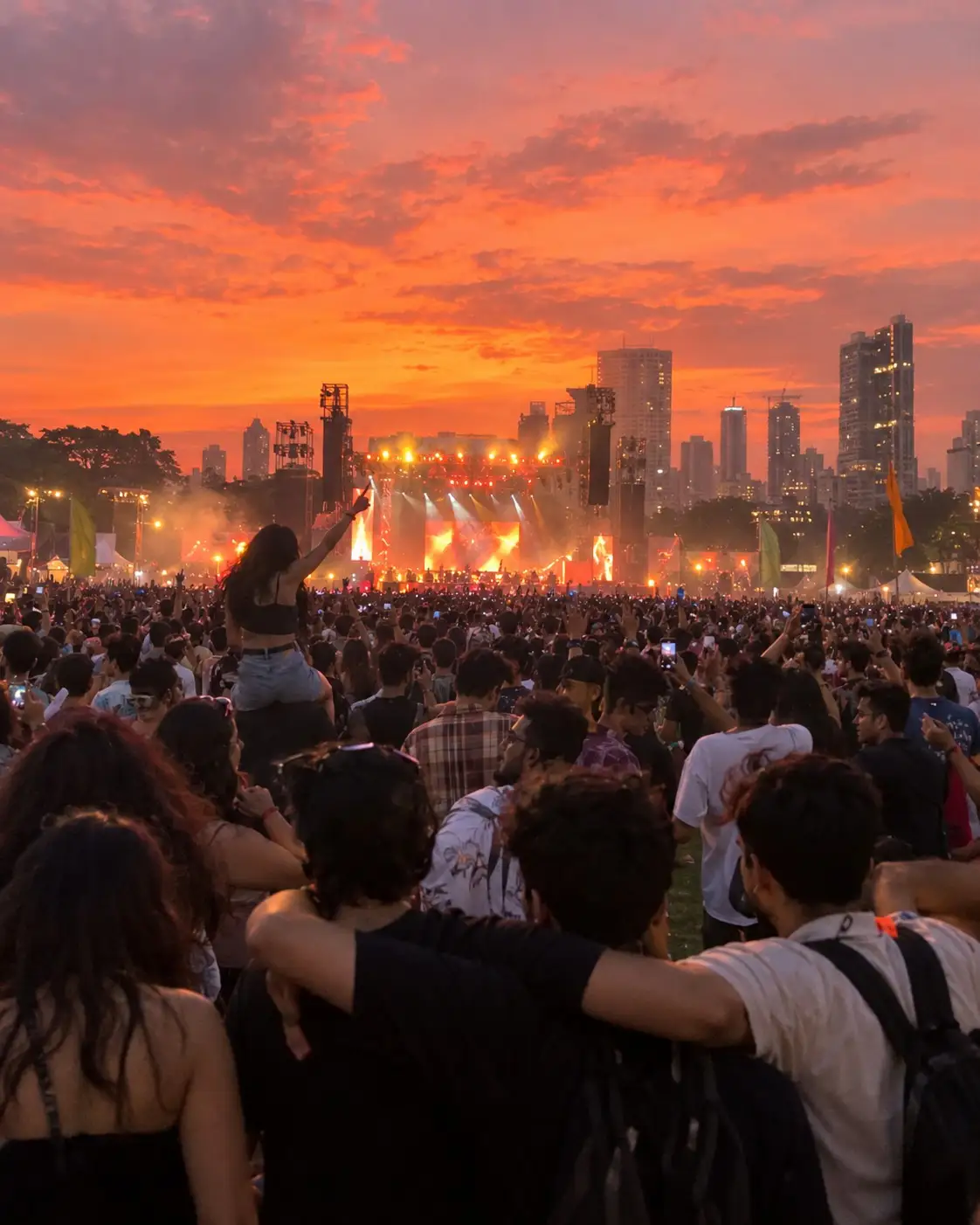 Illustration: friends with arms around each other in a big crowd facing a lit stage at sunset, city towers behind