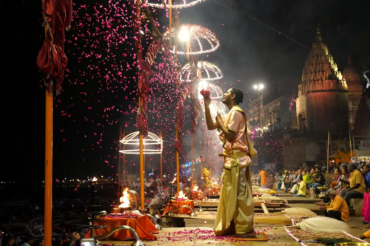 A priest at the evening Ganga Aarti in Varanasi, under falling rose petals