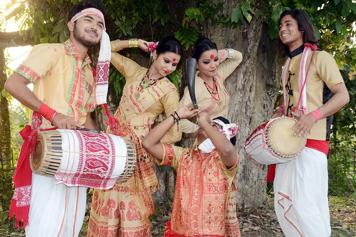 Young men and women in traditional dress performing the Bihu dance with dhols