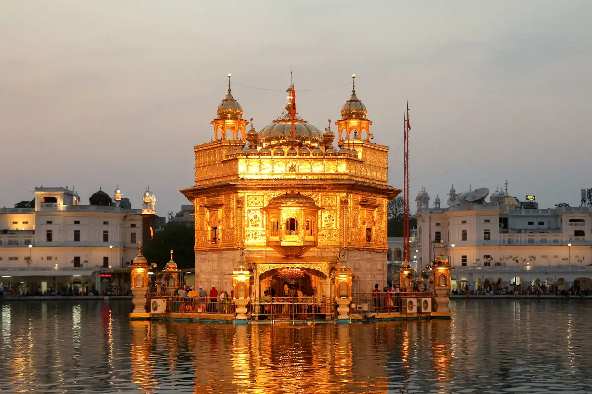 The Golden Temple in Amritsar glowing at dusk, reflected in the sarovar