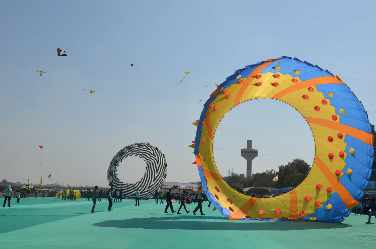 Giant ring-shaped display kites on the festival ground in Ahmedabad, small kites flying above
