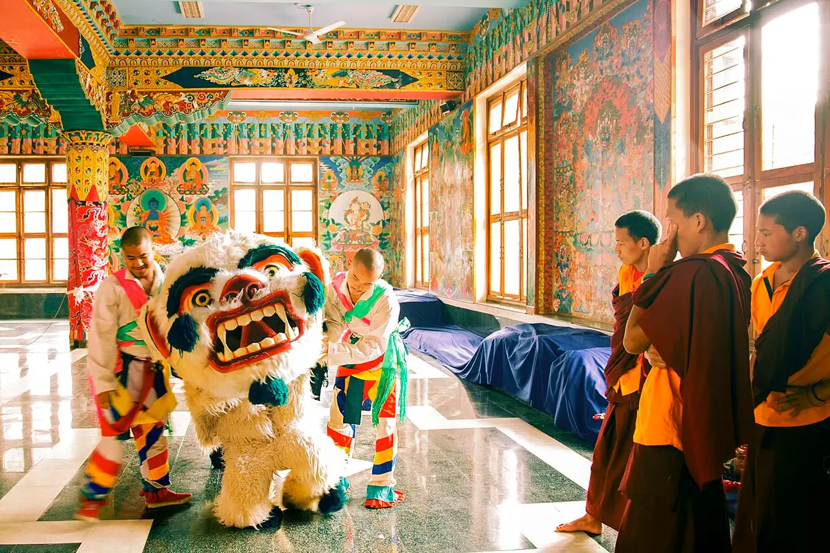A snow lion dancer and monks in a monastery hall getting ready for Losar