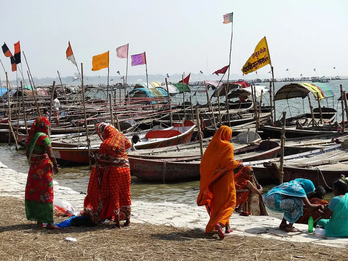 Women pilgrims on the Yamuna riverbank among boats at the Magh Mela, Prayagraj