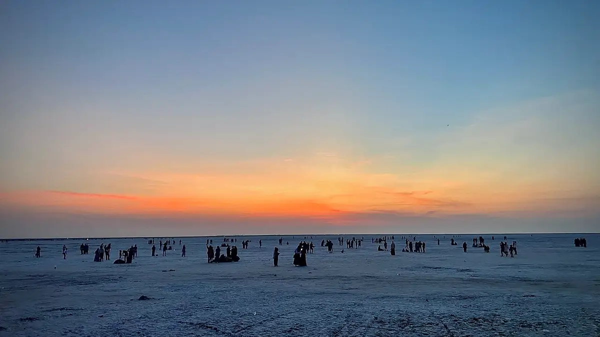 Visitors walking on the white salt desert at Rann Utsav at sunset